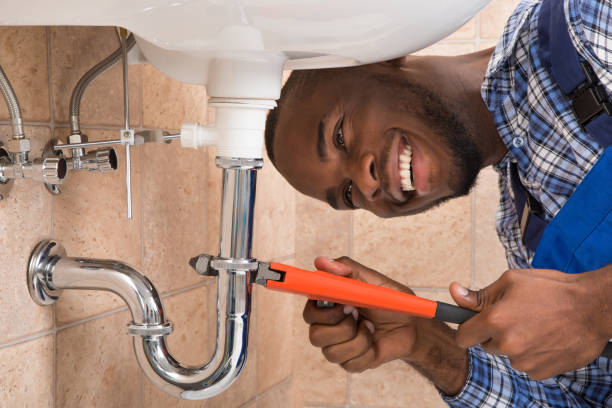 Close-up Of Happy Young African Male Plumber Repairing Sink In Bathroom Close-up Of Happy Young African Male Plumber Repairing Sink In Bathroom